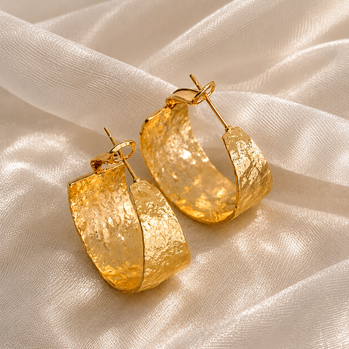 Chunky hammered gold huggie earrings on premium silk fabric backdrop